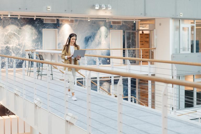 XMS 21 Frau gehend mit Laptop und Kopfhörern