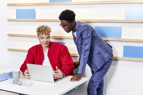 XMS 23 Mann sitzend und Frau stehend am Laptop